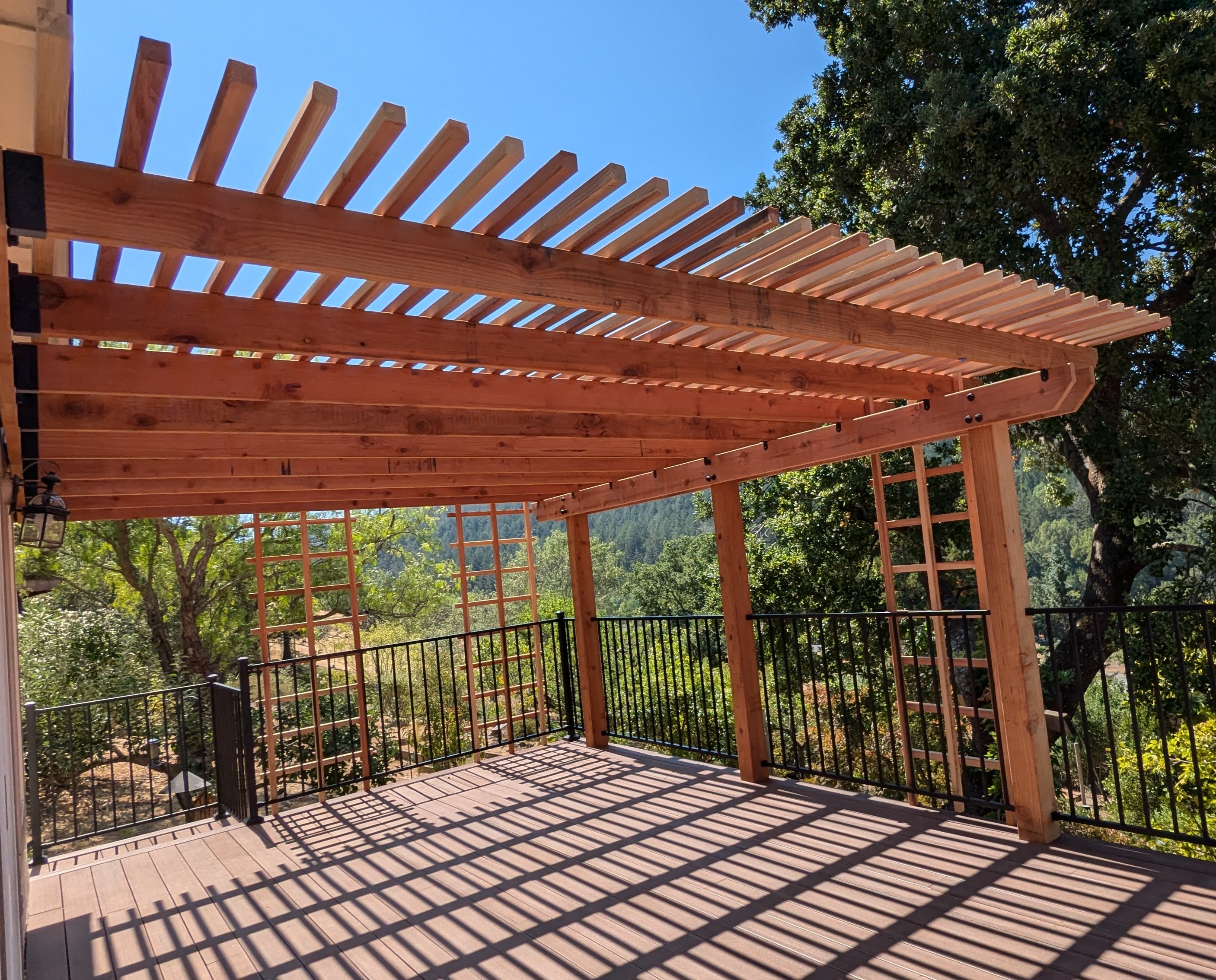 Redwood pergola with trellis panels over a composite deck built by QBR